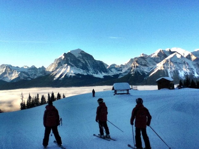 three skiers looking towards the mountains in the morning